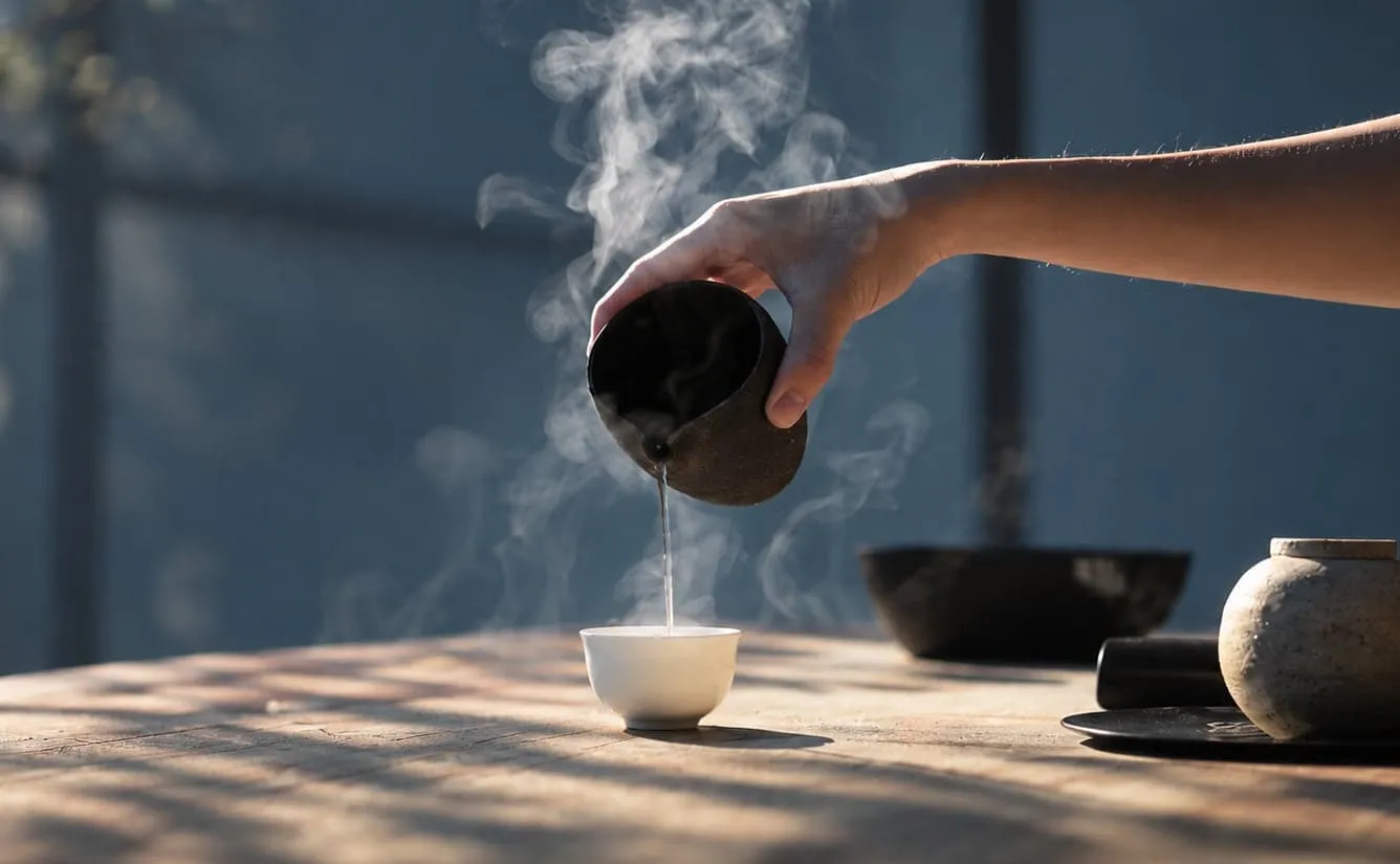 往白瓷小杯里倒茶，热气升起